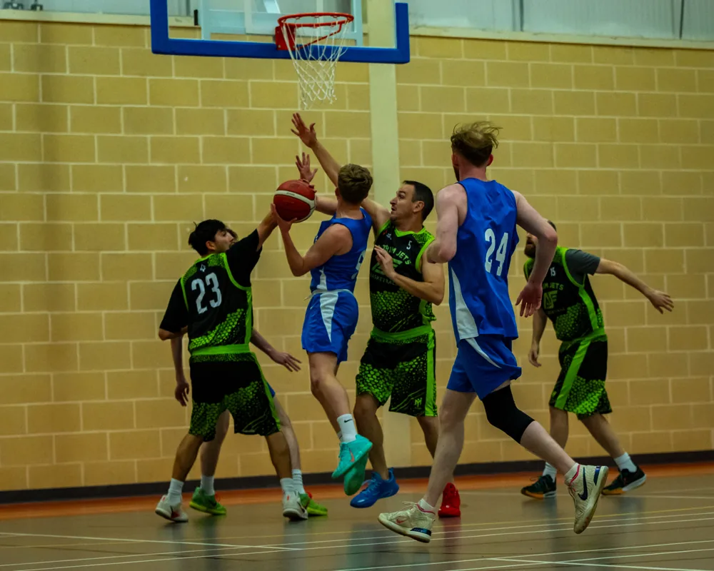 Basketball players contest the ball beneath the basket