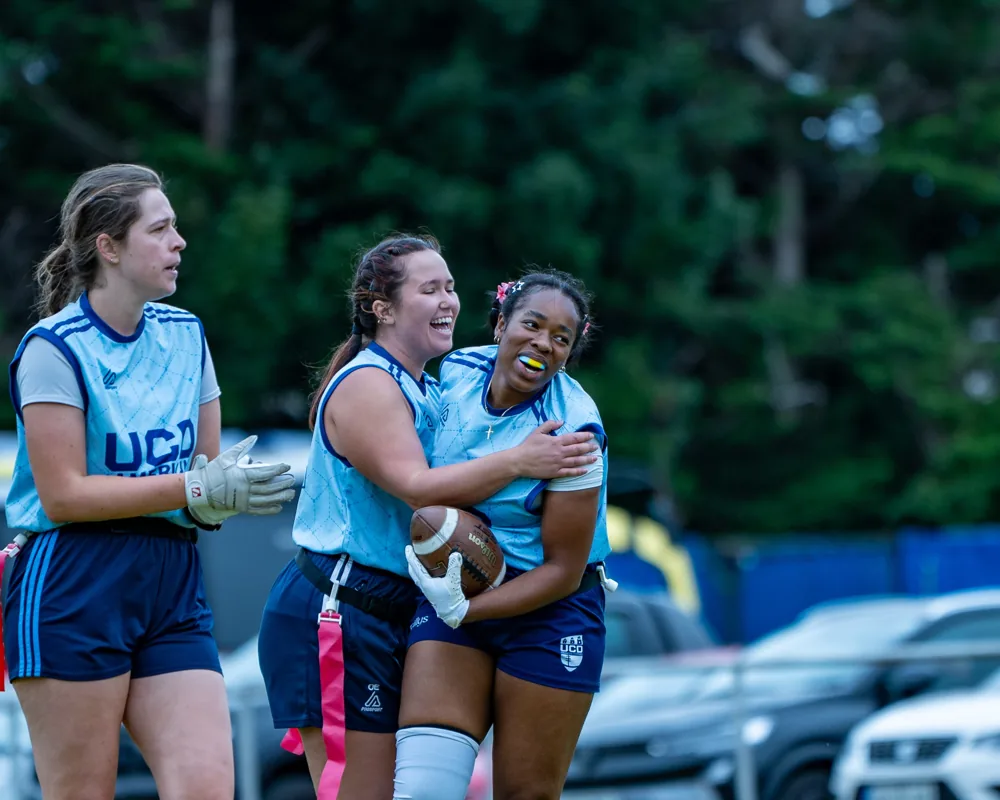 UCD teammates smile and embrace after a touchdown.