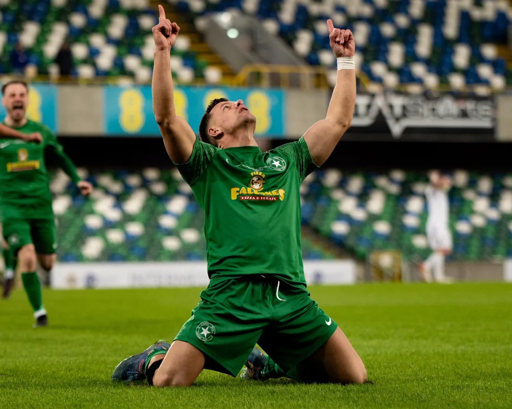 Football player celebrating on knees, stadium background
