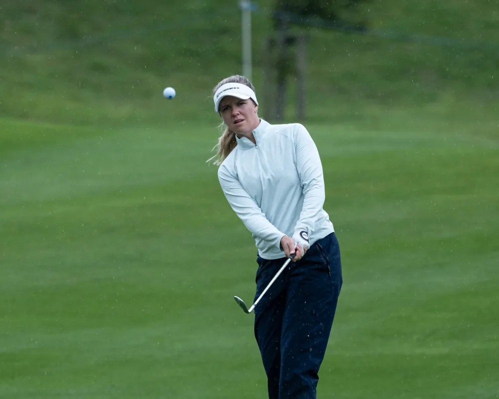 Golfer chipping ball against green background