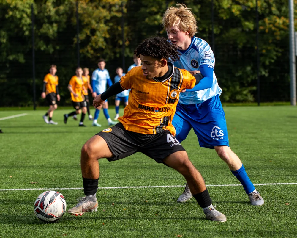 Two players compete shoulder to shoulder. H&W Welders Reserves v Warrenpoint Reserves.