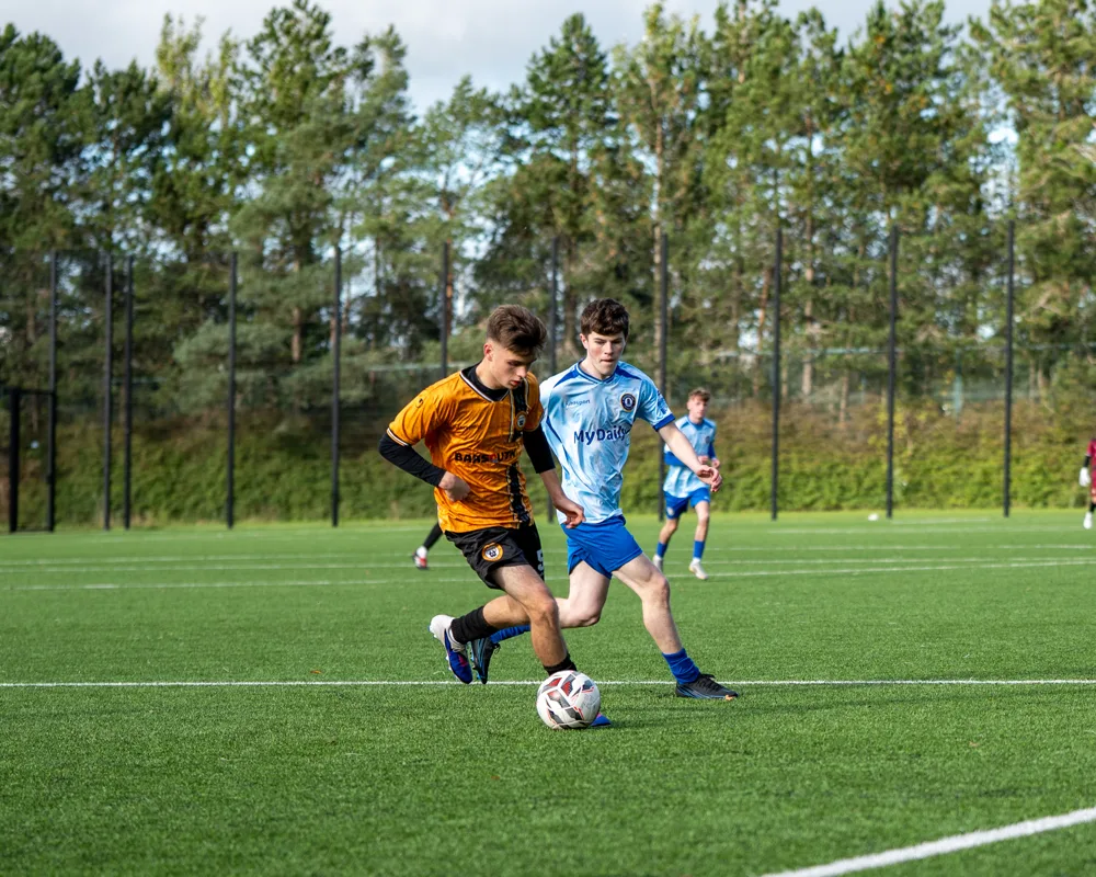 Two players pursue possession. H&W Welders Reserves v Warrenpoint Reserves.