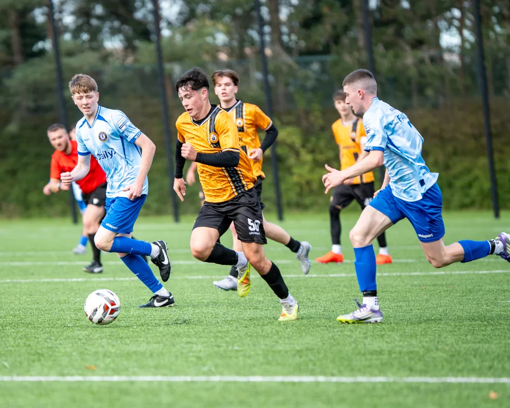 Player carries the ball past opponents. H&W Welders Reserves v Warrenpoint Reserves.