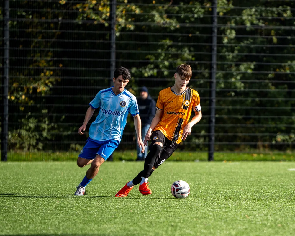 Two players chase the ball. H&W Welders Reserves v Warrenpoint Reserves.