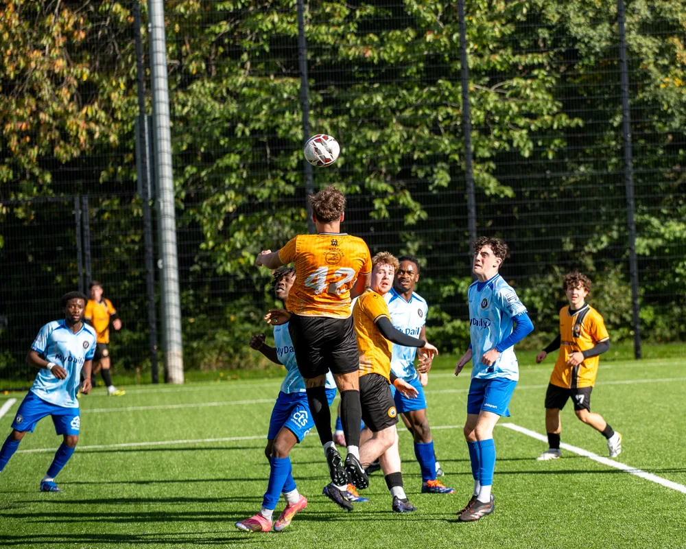 Players jump to meet the ball. H&W Welders Reserves v Warrenpoint Reserves.