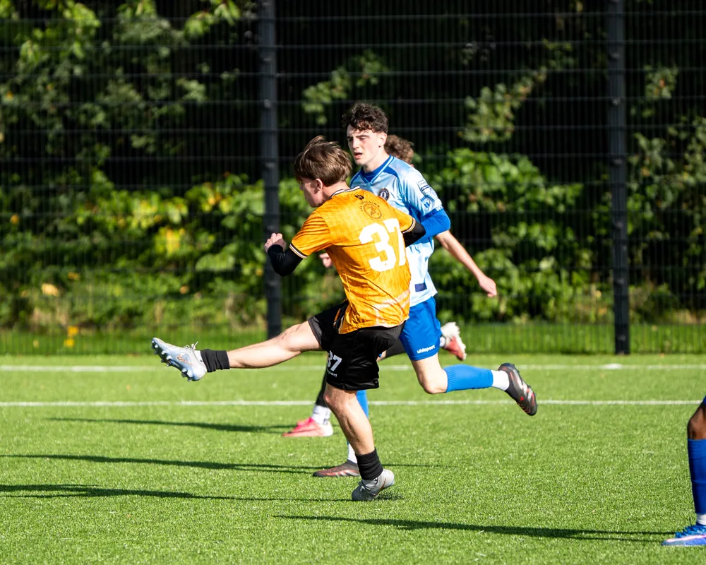 Player in amber strikes the ball. H&W Welders Reserves v Warrenpoint Reserves.