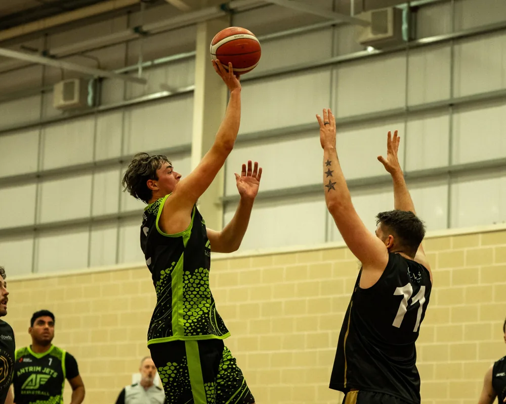 An Antrim Jets player rises for a shot as a Magherafelt Titans defender contests.