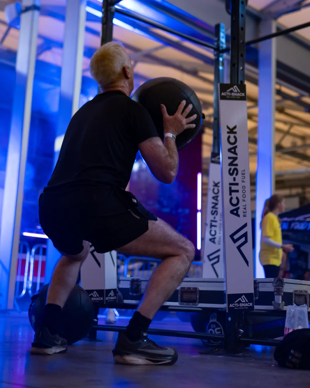 Athlete works at a wall-ball station. Mecca Sim 5.