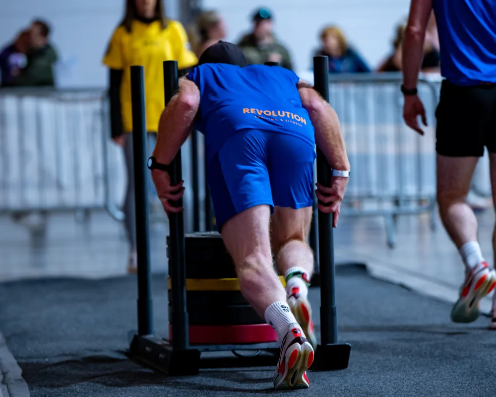 Athlete leans into a weighted sled. Mecca Sim 5.