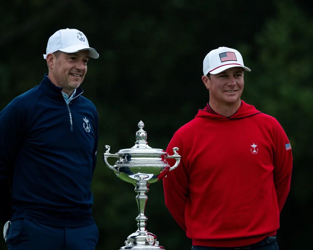 Two golfers stand beside the PGA Cup trophy.