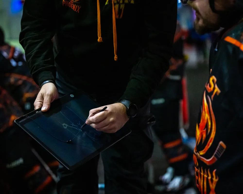 Hands and a clipboard beside the rink
