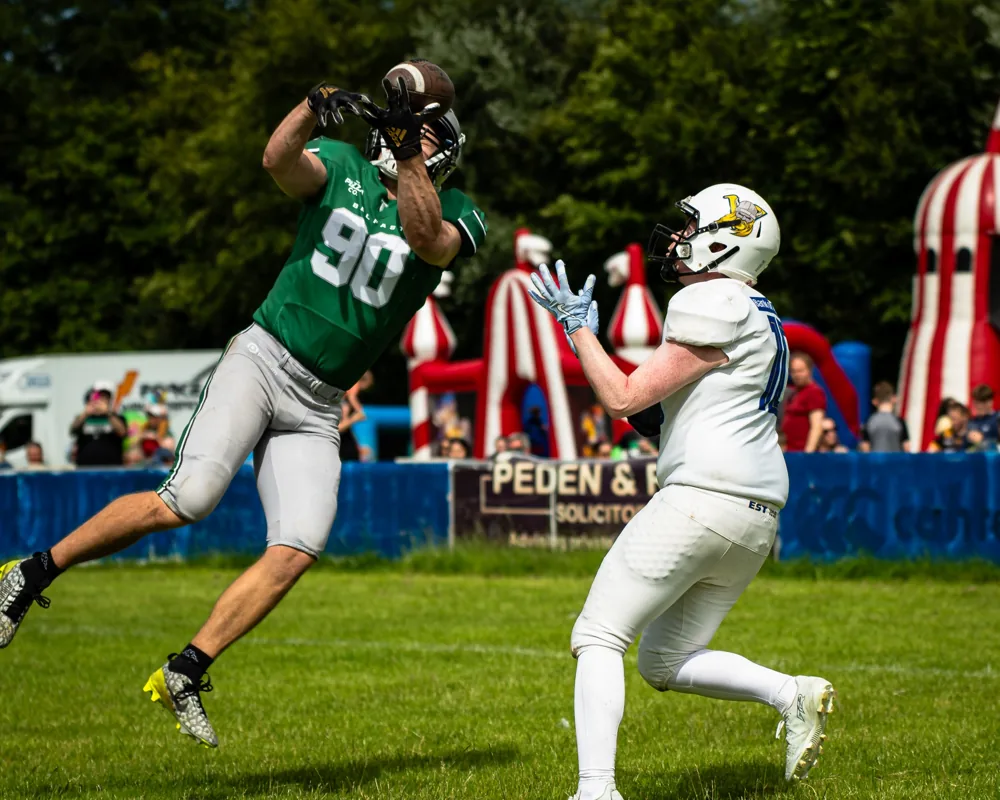 A Belfast Trojans receiver reaches above a UL Vikings defender to catch the ball.