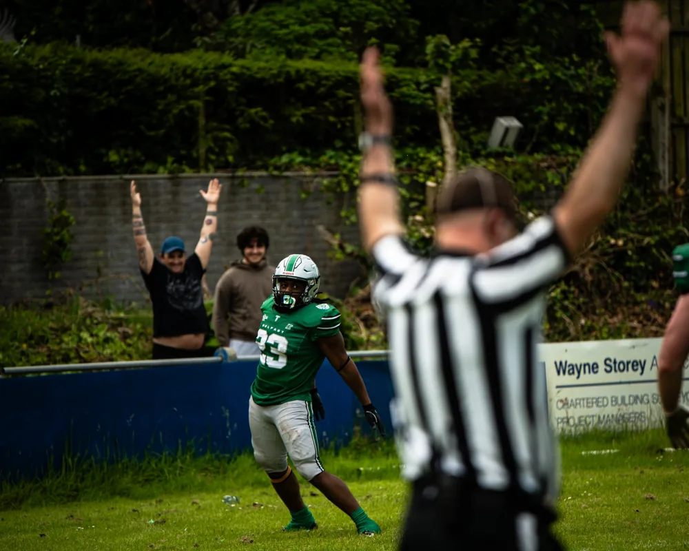 An official signals a touchdown with Belfast Trojans player Kevin Sungo beyond him.
